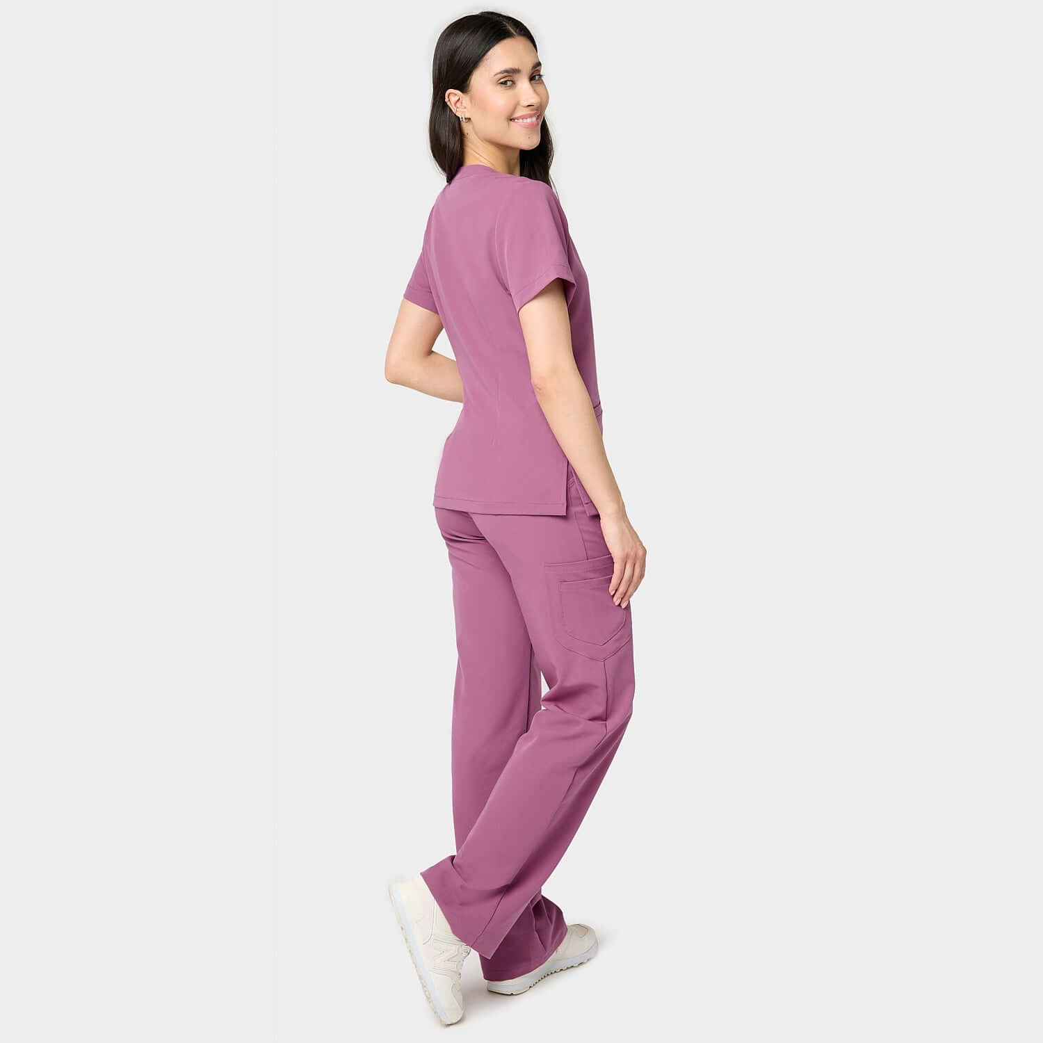 Modelka w bluzie medycznej Emily w kolorze Berry Crush, z dekoltem w serek, krótkim rękawem i kieszeniami – elegancka i funkcjonalna odzież medyczna dla kobiet.